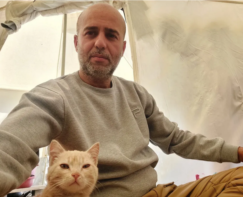 A man and a ginger cat in a tent in Gaza