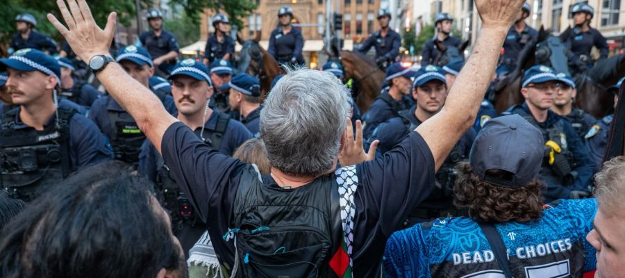 man holding arms up facing down police line in sydney 