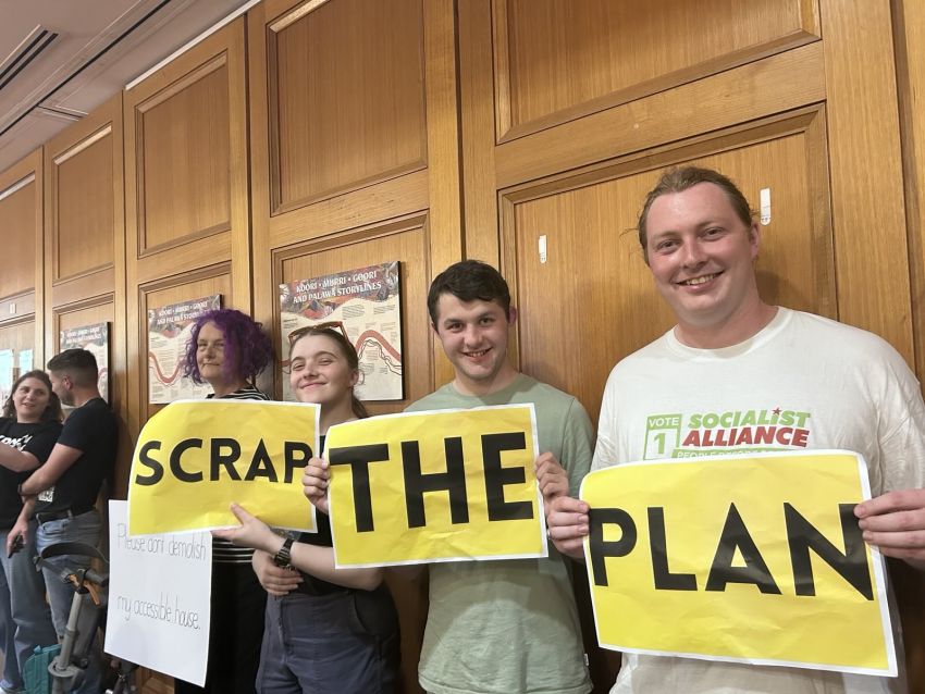 people holding signs that read: 'scrap the plan'