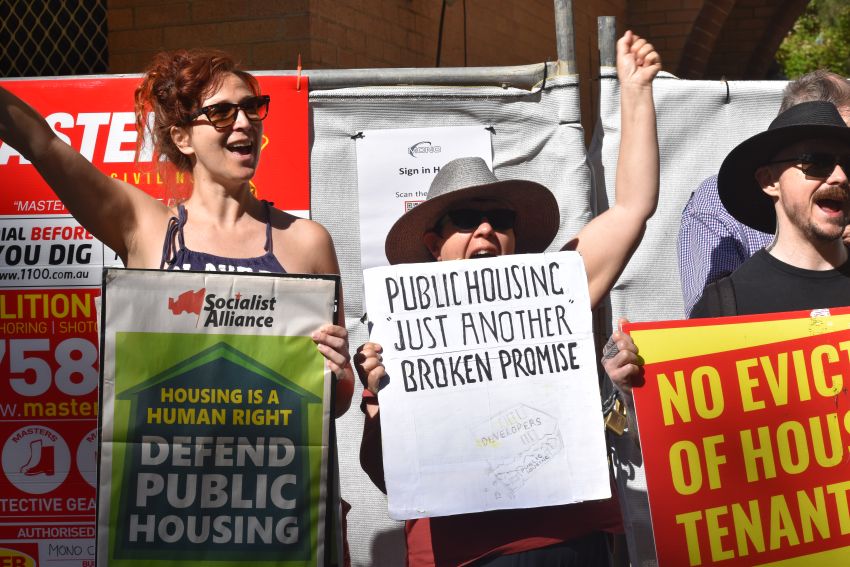 people holding signs supporting public housing