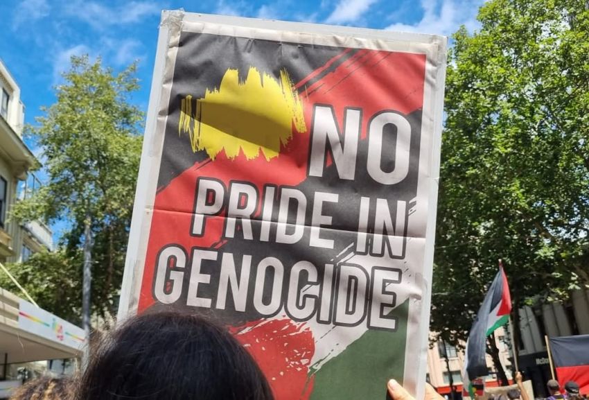 Photo of person holding placard that with text 'No pride in genocide'