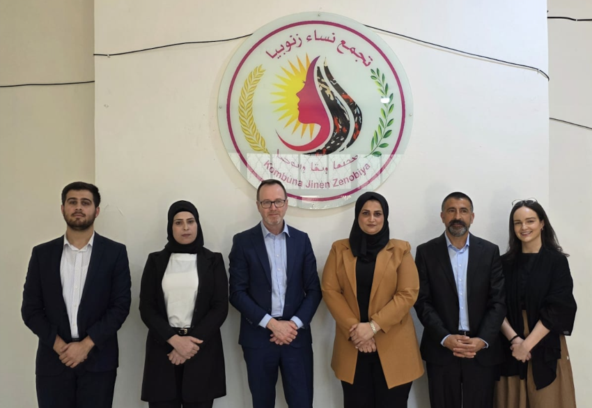 Members of the delegation standing in front of a sign indoors