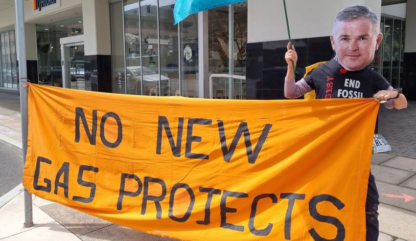 Cropped photo of Extinction Rebellion South Australia protestor holding No New Gas Projects banner and Extinction Rebelllion flag