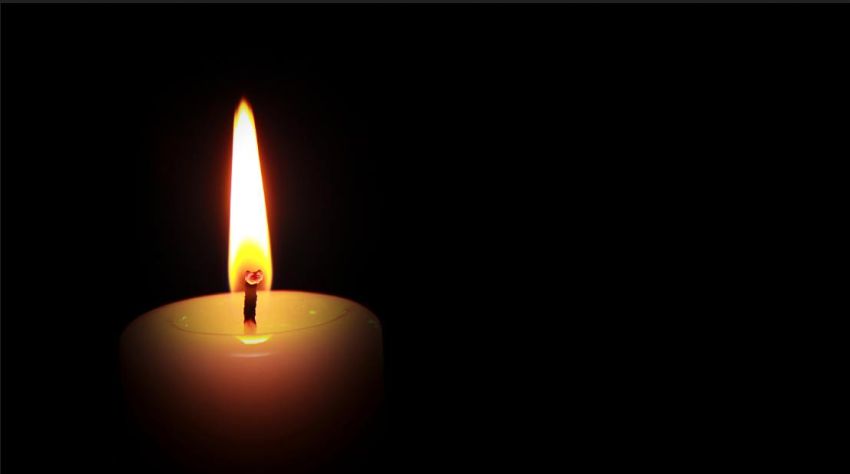 Photo of a lit candle against a dark background