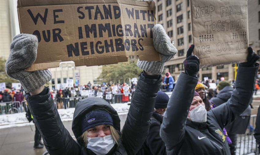 Anti-ICE protestor holding pro-migrant placards at anti-ICE protest in US