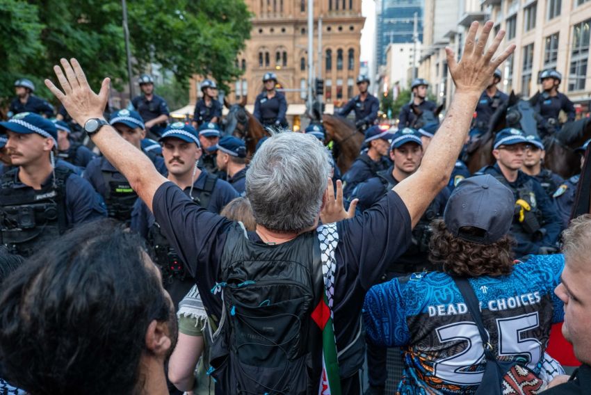 man holding arms up facing down police line in sydney 
