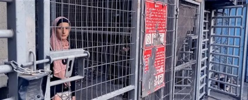 Still from Palestinians Don't Need Sidewalks: women stands behind fence 