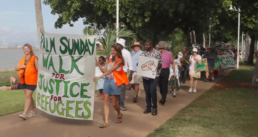 Participants at a Palm Sunday Walk for Justice and Refugees in Townsville with a large hand-painted banner leading a walk