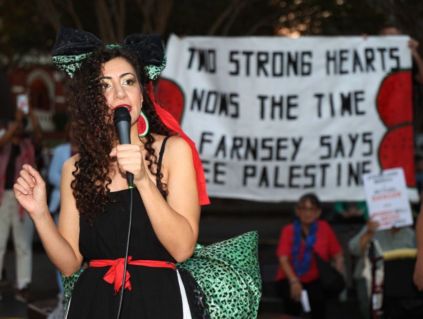 Justice for Palestine activist Remah Naji in front of a banner reading 'two strong hearts, now's the time, Farnsey says Free Palestine', April 17