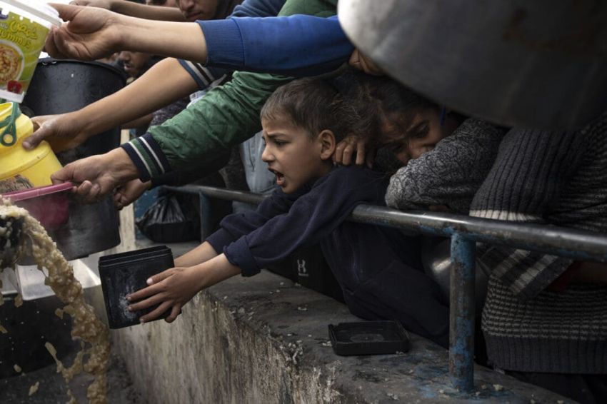 Palestinian boy reaches out with saucepan for food