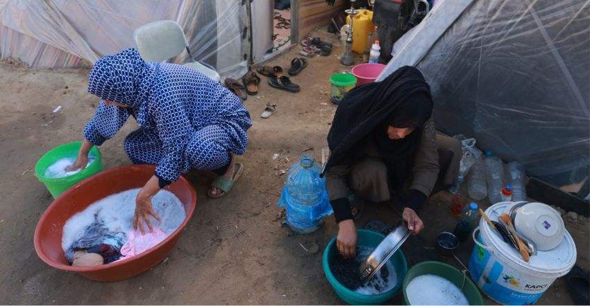 Palestinian women washing outside tents