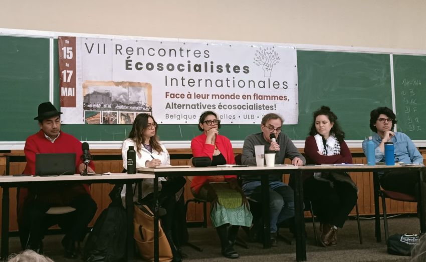 people sitting at a table with a banner on the wall behind them