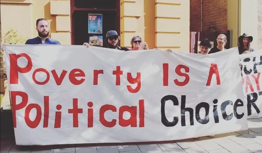 Protesters holding a banner that says "Poverty is a politcal choice"