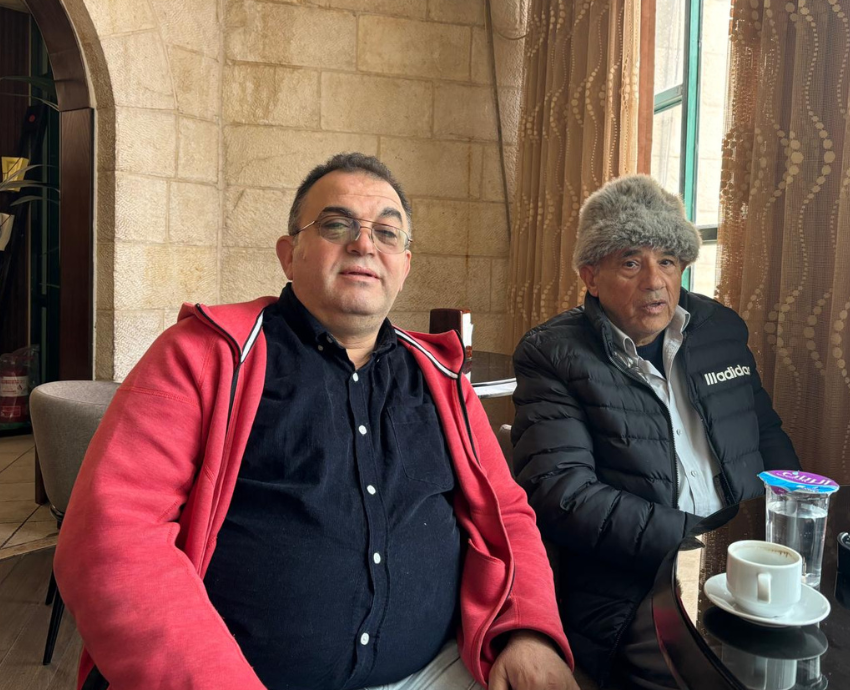 two men sitting at a table in a cafe