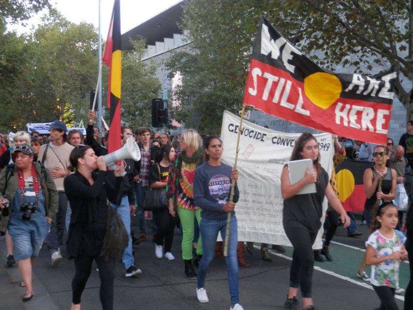 Protesters marching, chanting and holding banners and placards.