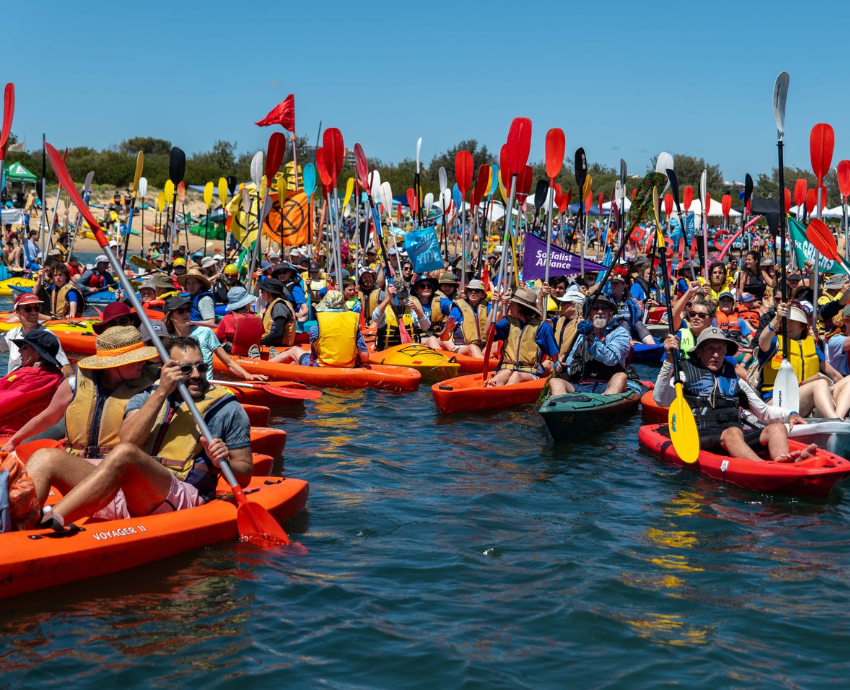 people in kayaks waving flags