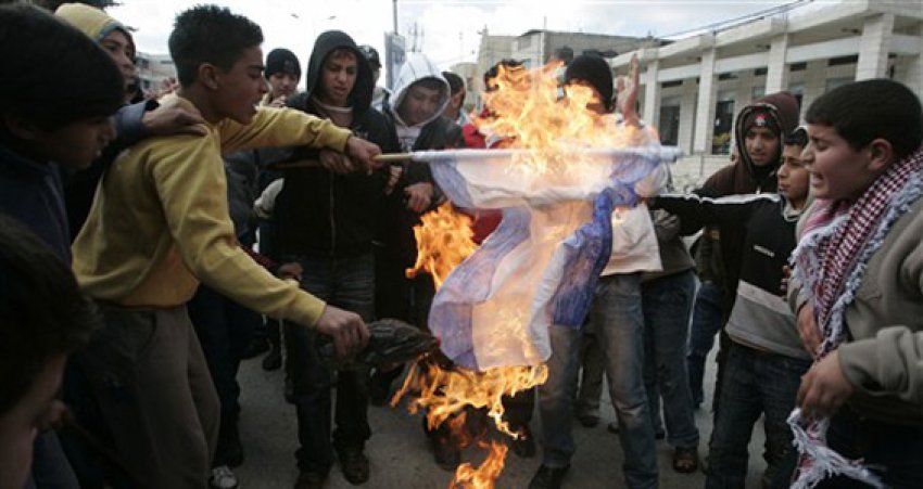 Palestinians in the West Bank burn the Israeli flag.