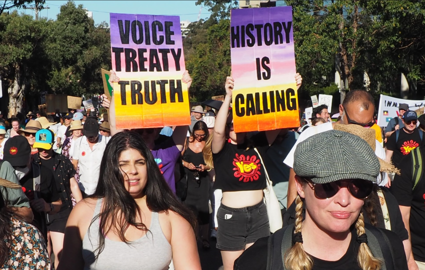 Protest march of supporters for the YES case with two prominent signs: 'Voice Treaty Truth' on the left, 'History is Calling' on the right.