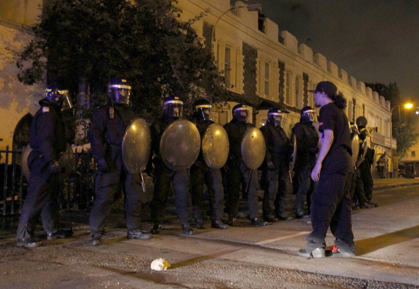 Man stands in front of riot police