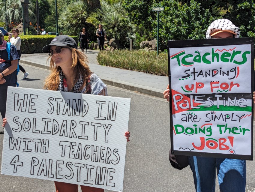 A person holding a sign that says: "We stand in solidarity with Teachers 4 Palestine"