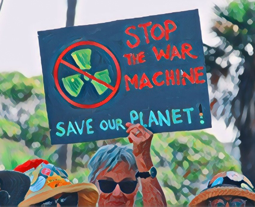 Protester holds sign reading 'Stop the war machine: Save our planet!'