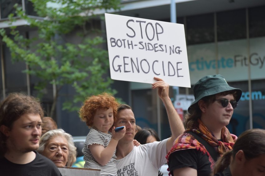 Protester holds sign that reads: stop both-sidesing genocide at ABC protest