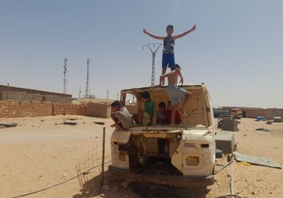 children playing on a van in a desert refugee camp