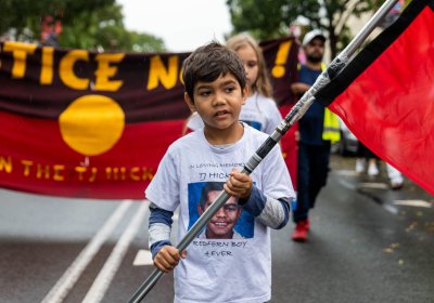 A young indigenous child carrying an Aboriginal flag at a demonstration