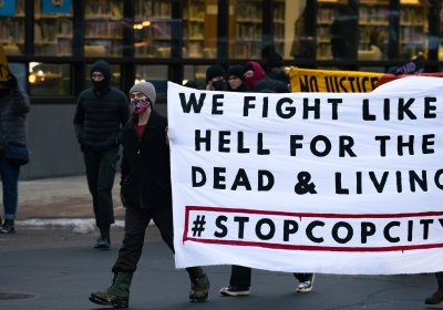Protesters hold sign reading 'We fight like hell for the dead & living. #stopcopcity.'
