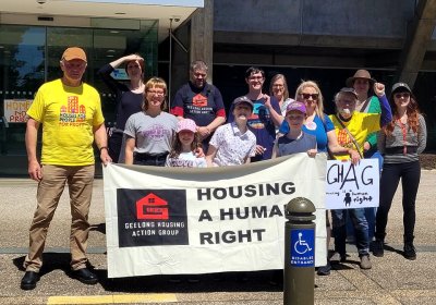 Housing activists rally outside Homes Victoria holding sign that says "Housing is a human right"