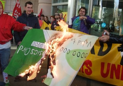 Protesters burning a Basics Card in effigy