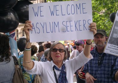 Protesters holding refugee rights sign that says 'We welcome asylum seekers.'