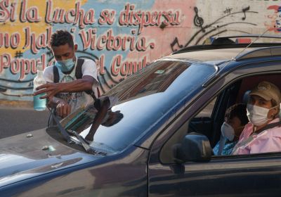 man with a mask washes a car window in Venezuela