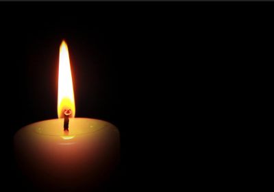 Photo of a lit candle against a dark background