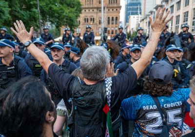 man holding arms up facing down police line in sydney 