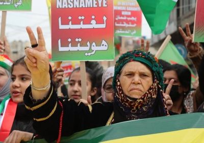 Woman makes a peace sign at a protest in Qamishlo
