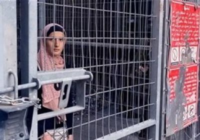 Palestinian woman stands behind border fence