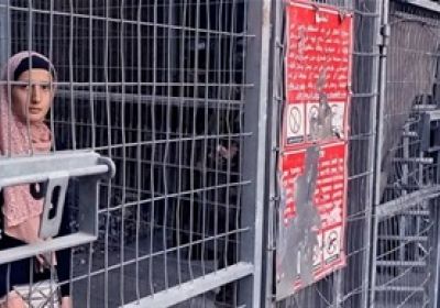 Still from Palestinians Don't Need Sidewalks: women stands behind fence 