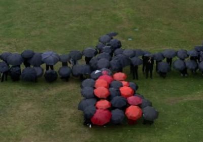 Photo of a black cockatoo formed by people holding black and red umbrellas