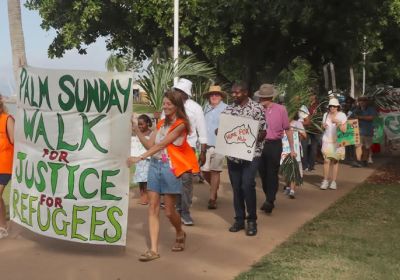 Participants at a Palm Sunday Walk for Justice and Refugees in Townsville with a large hand-painted banner leading a walk