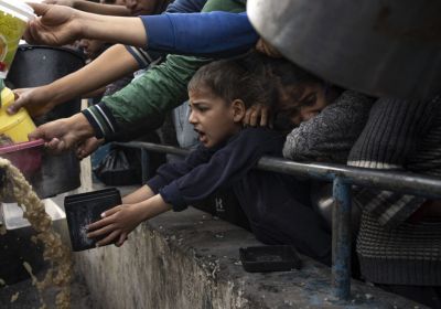 Palestinian boy reaches out with saucepan for food
