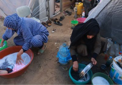 Palestinian women washing outside tents