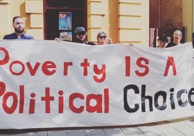 Protesters holding a banner that says "Poverty is a politcal choice"