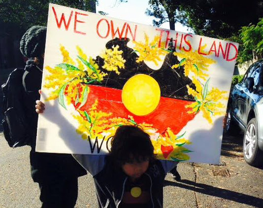 We Own This Land placard.